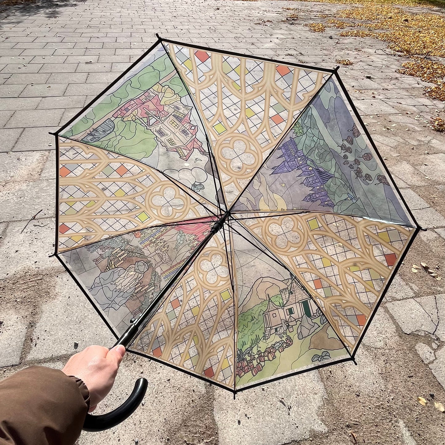 Colorful umbrella with artistic design held by a person on a sidewalk.